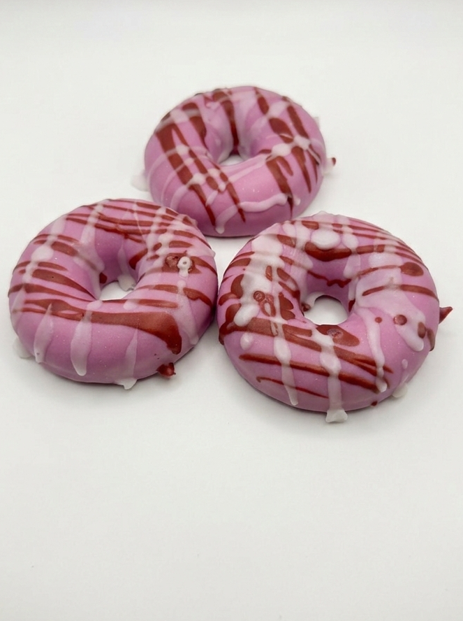 Three pink and white striped donut-shaped soaps on a white background