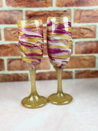 Set of 2 elegant champagne flutes with gold, pink, and white swirl design on sturdy bases