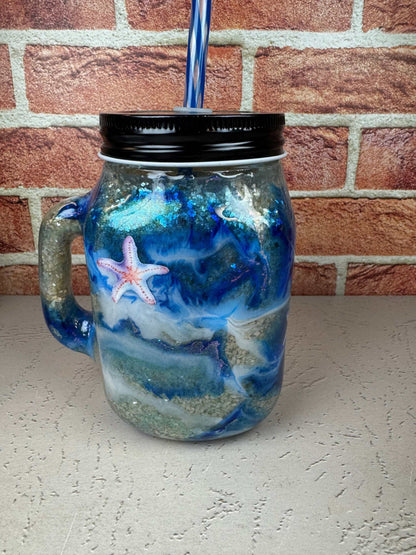 Seashell mason jar mug with ocean design and starfish detail, blue straw, beach-themed drinkware
