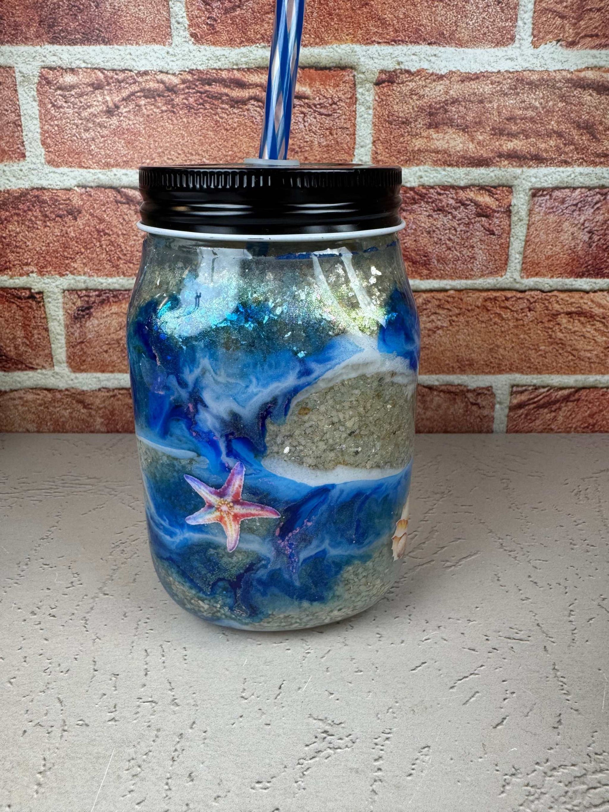 Seashell Mason Jar Mug with blue ocean design, sand texture, starfish detail, black lid, and blue striped straw 
