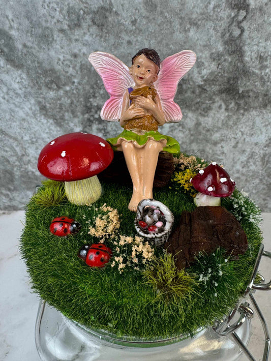 Magical fairy garden jar with pink fairy, red mushrooms, ladybugs, and green moss miniature decor