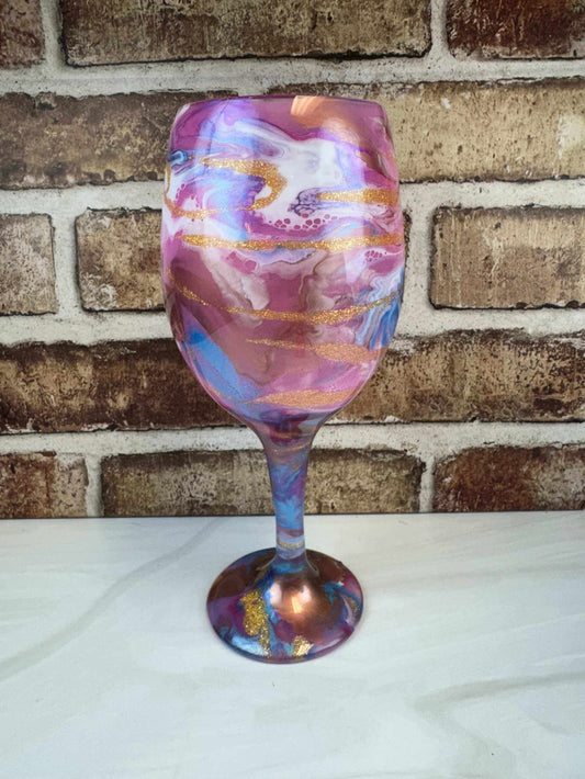 Handcrafted wine glass with pink, bronze, and white swirls and smooth finish.