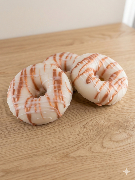 Two doughnut-shaped SOAPS with a white and brown striped pattern on a wooden surface.