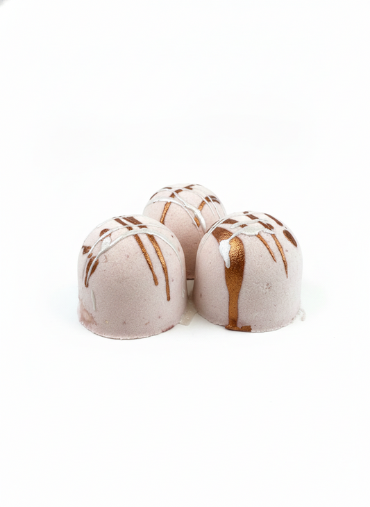 Three bath bombs with brown drizzle on a white background
