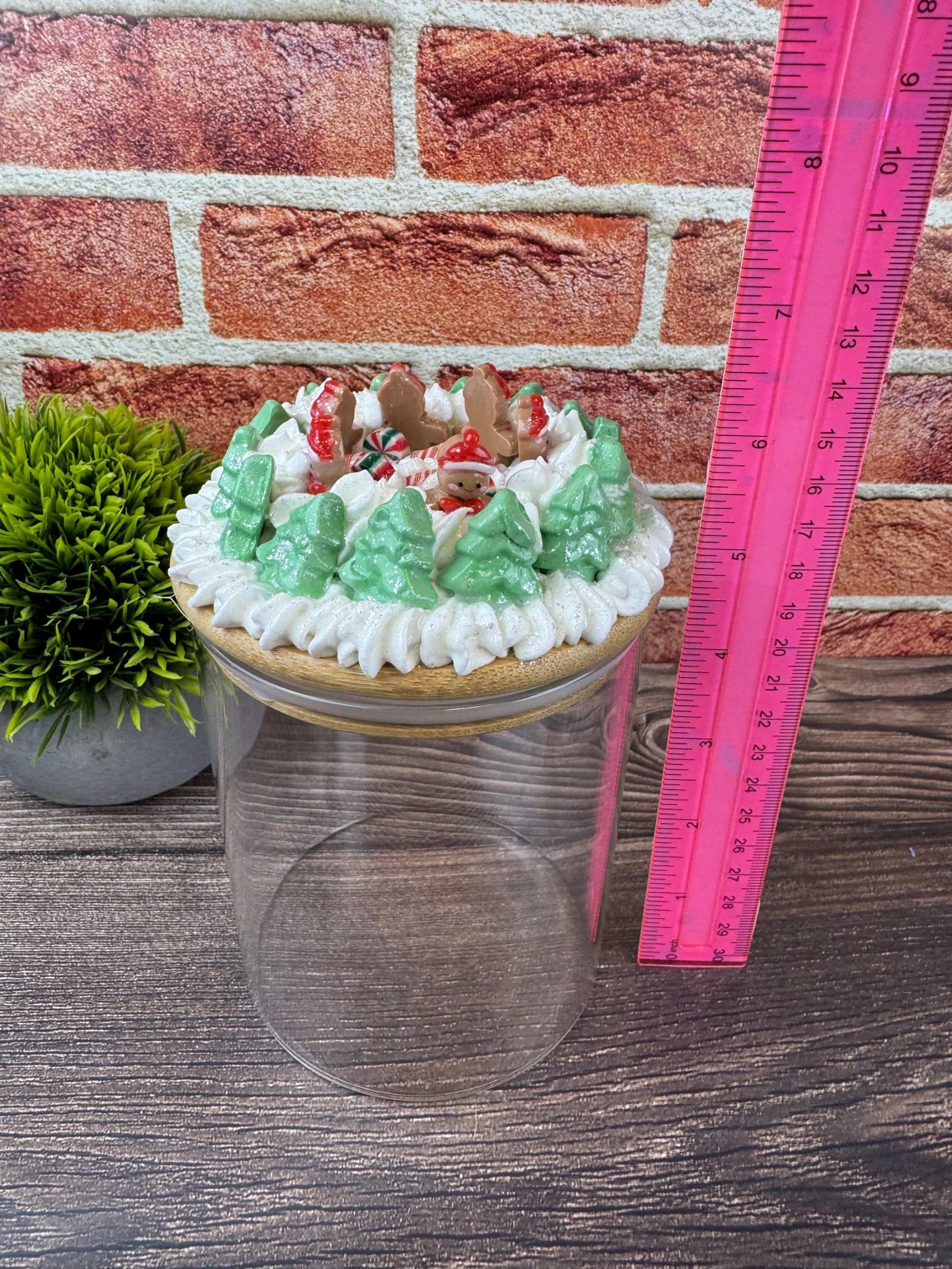 Clear Christmas jar decor with gingerbread and green tree accents on lid and pink ruler showing size