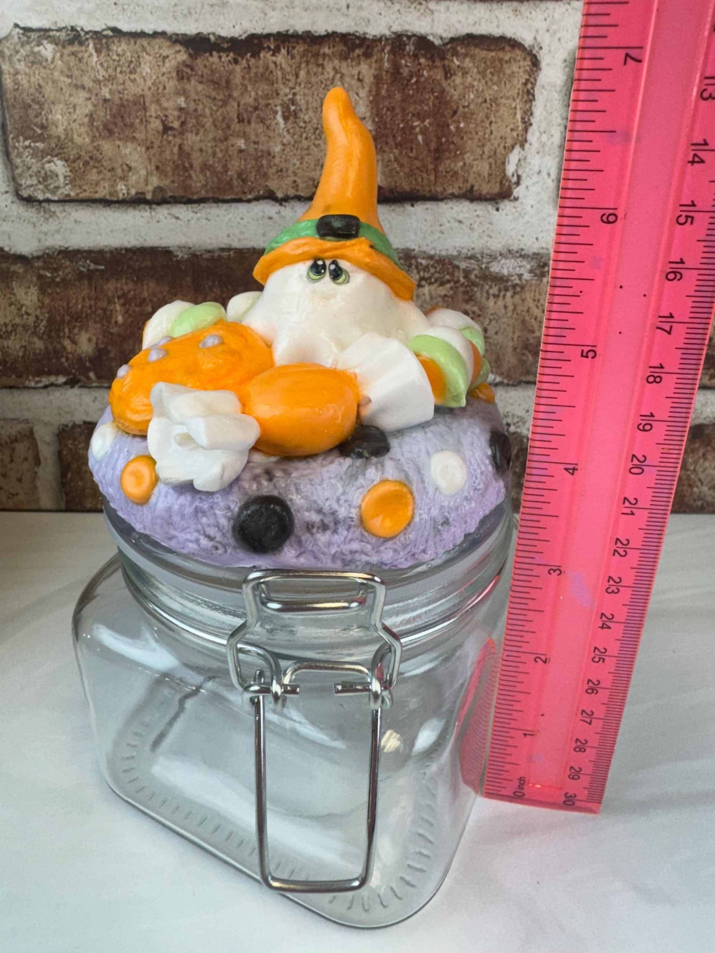 Spooky Sweet Treat Jar with handcrafted faux ghost, pumpkin, and candy lid decoration next to a pink ruler showing size
