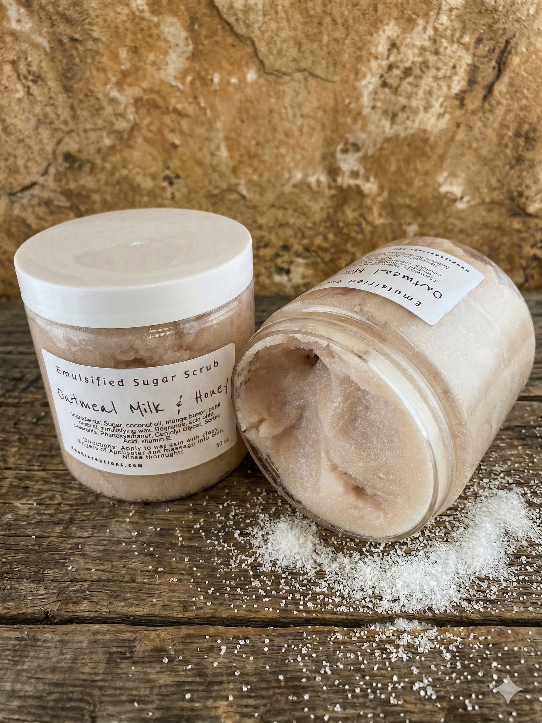 Two jars of emulsified sugar scrub on a wooden surface with a stone background